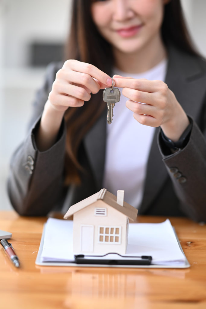 Smiling real estate agent holding house keys. Mortgage and real